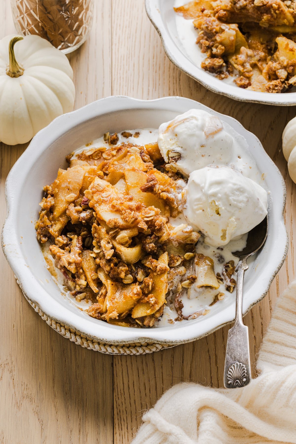 Apple pumpkin crisp with vanilla ice cream in a white bowl.