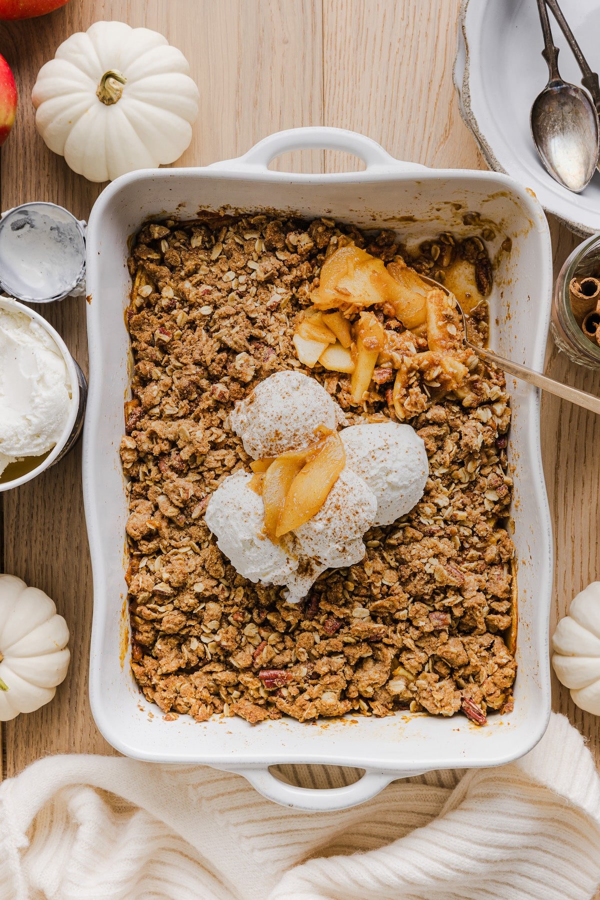 Baked pumpkin apple crisp in a baking dish topped with vanilla ice cream.