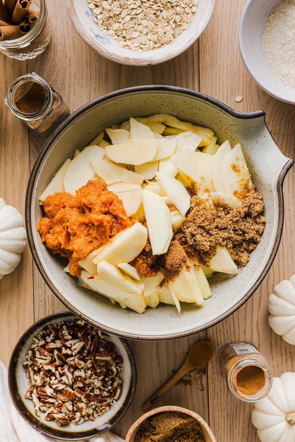 Ingredients for pumpkin apple crisp in a large bowl about to be mixed.