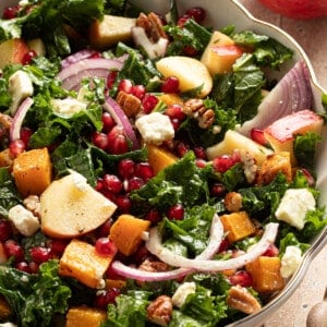 Kale and butternut squash salad with apple and pomegranate seeds in a large bowl.