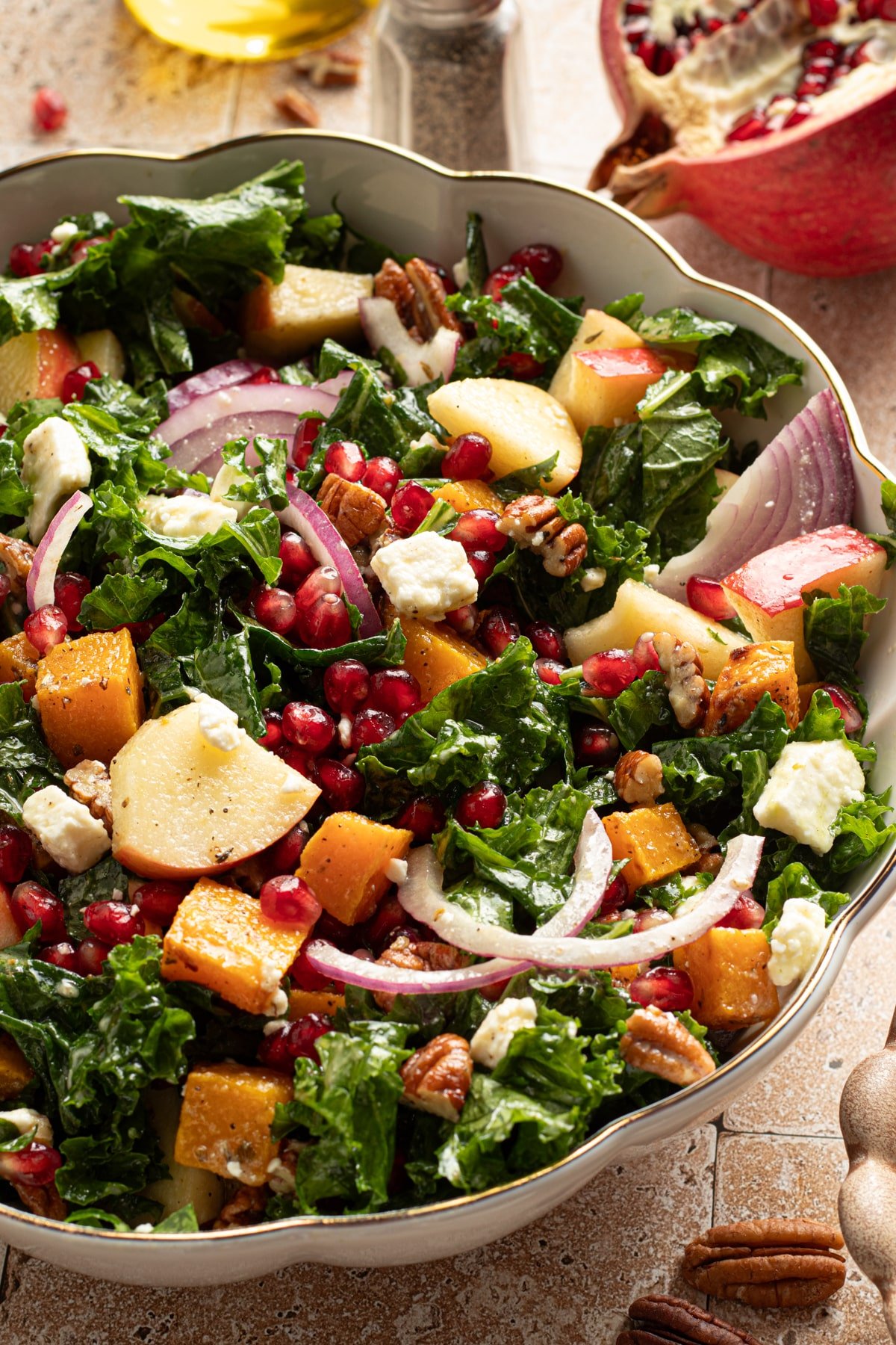 Kale and butternut squash salad with apple and pomegranate seeds in a large bowl.