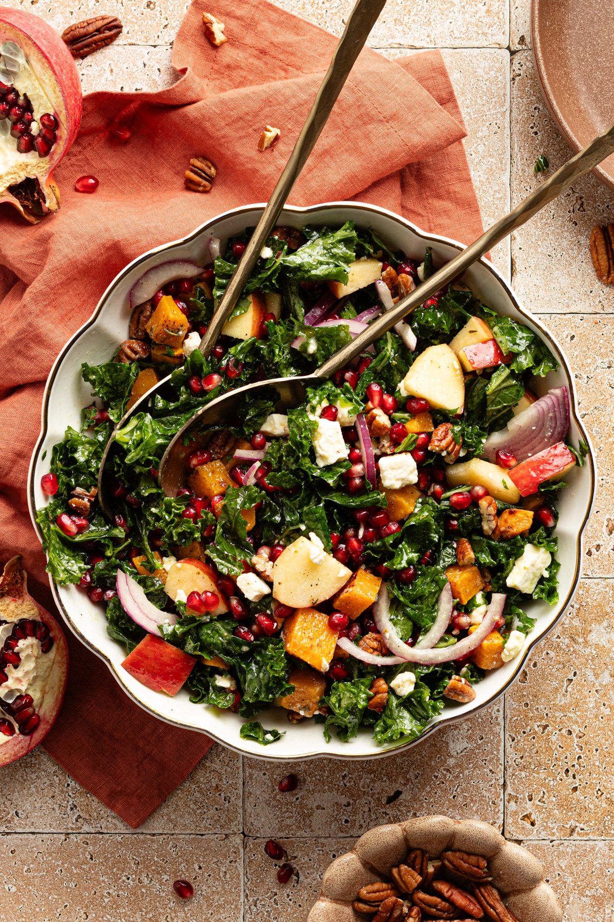 Kale and butternut squash salad with apple and pomegranate seeds in a large bowl.
