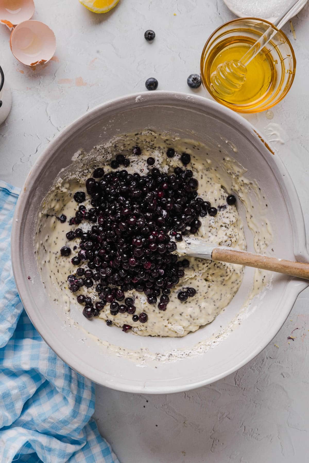 The blueberries on top of the batter in a bowl before mixing together.