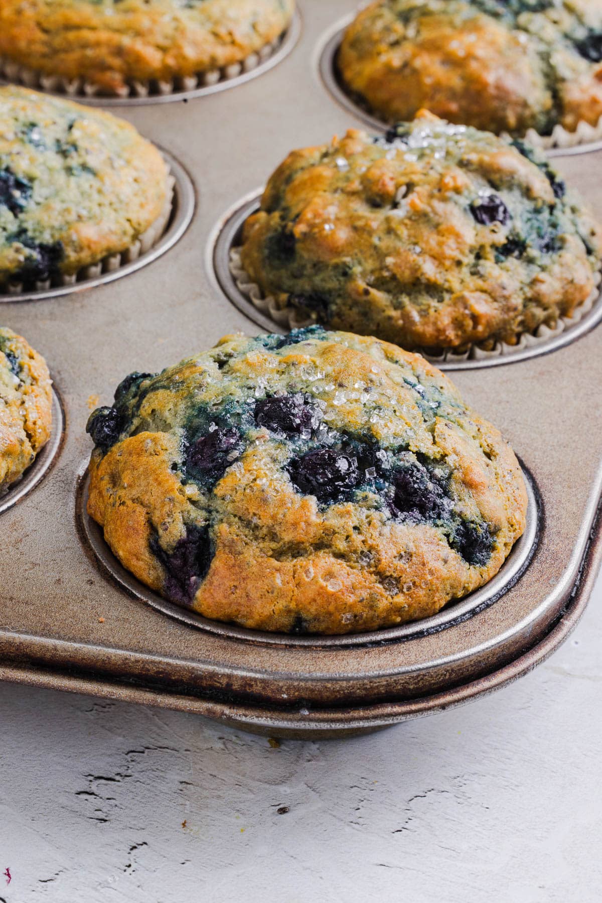 A baked blueberry muffin in a muffin tin.
