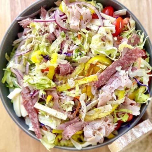 Grinder salad mixed in a bowl with Italian bread on the side