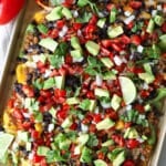 Bell pepper nachos on a sheet pan topped with pico de gallo, avocado and cilantro.