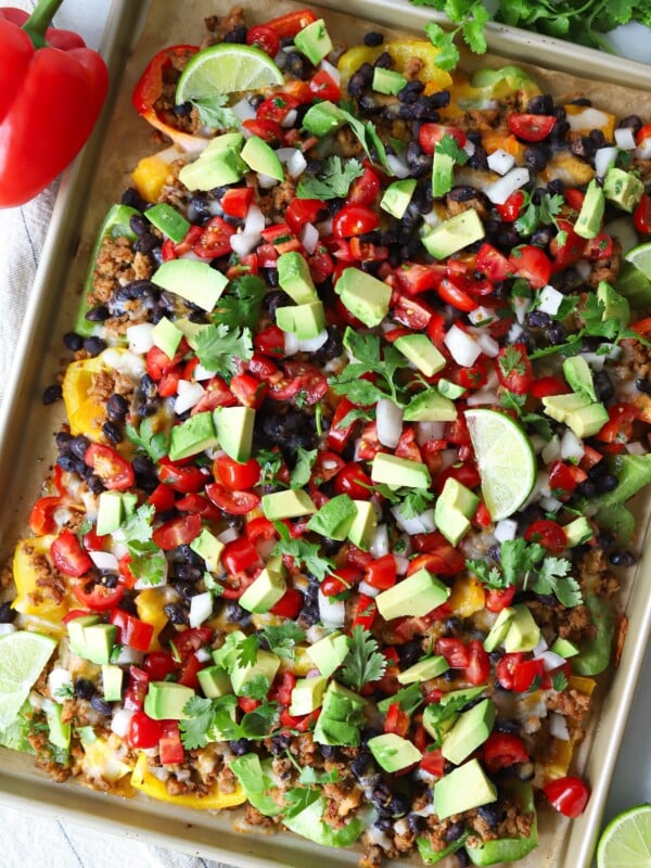 Bell pepper nachos on a sheet pan topped with pico de gallo, avocado and cilantro.