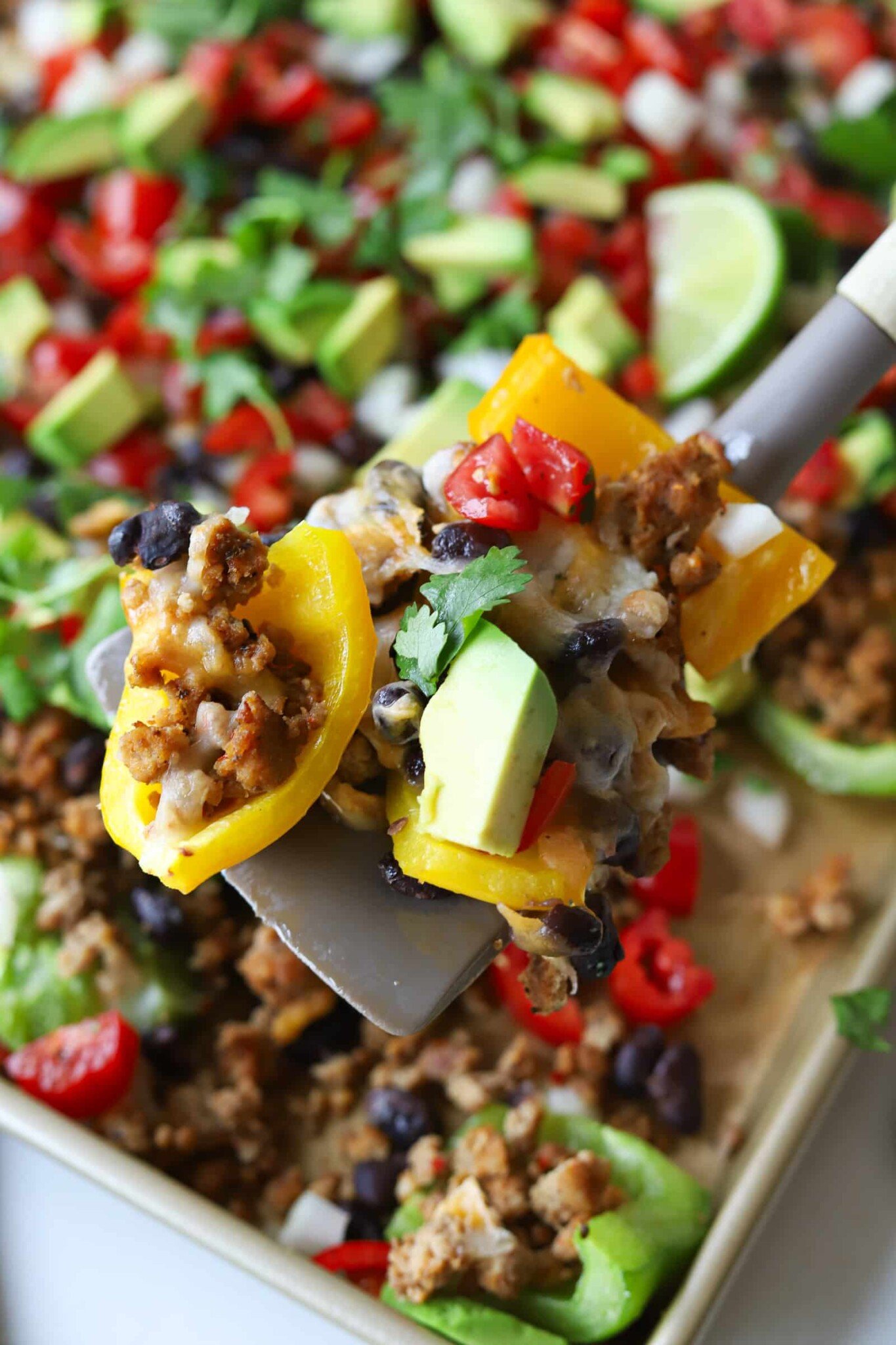 A spatula scooping up bell pepper nachos.