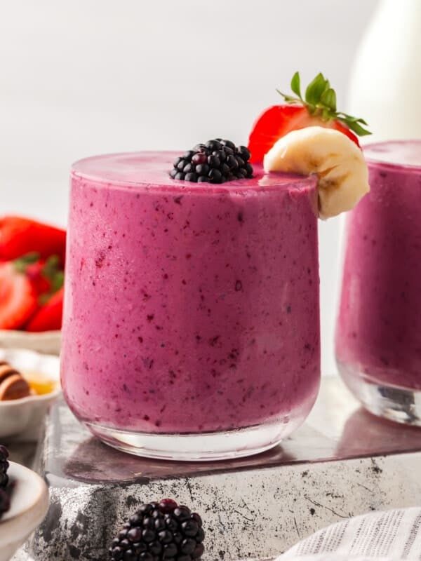 A blackberry smoothie garnished with blackberry strawberry and banana in a glass.