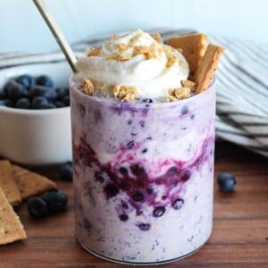Blueberry cheesecake overnight oats topped with whipped cream and graham crackers.