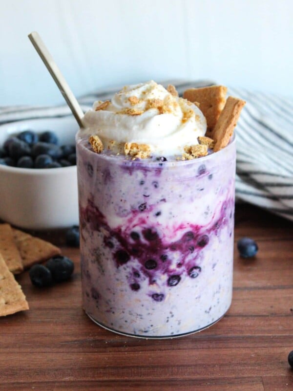 Blueberry cheesecake overnight oats topped with whipped cream and graham crackers.