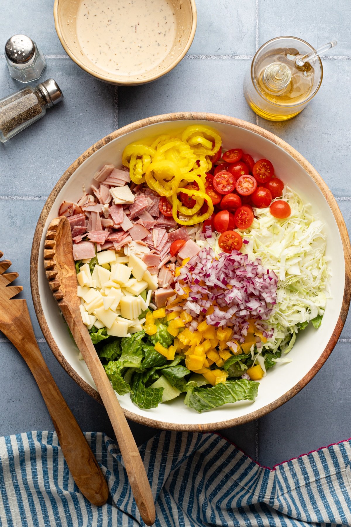Ingredients for grinder salad in a large bowl with a wooden spoon.