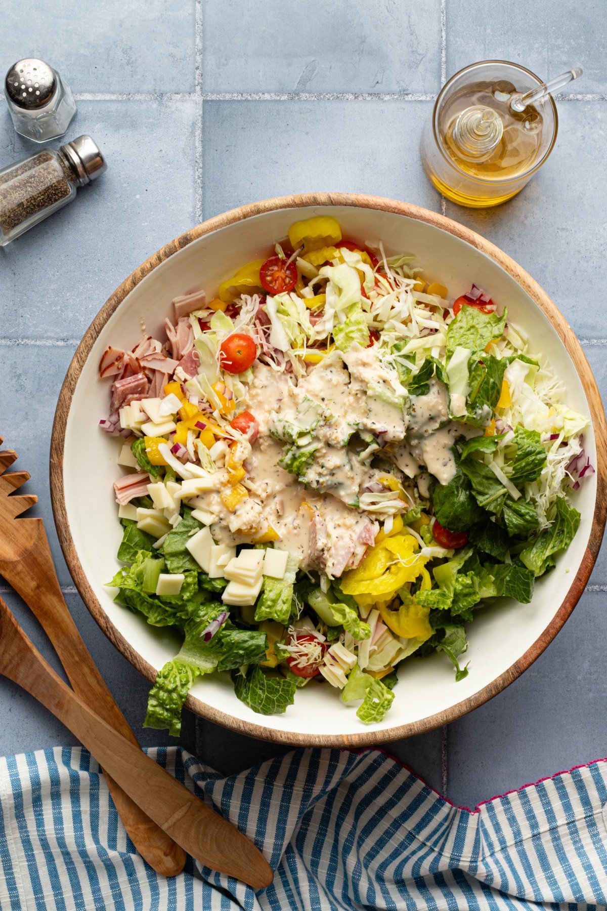 Creamy Italian dressing poured onto grinder salad in a bowl.