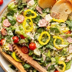 Italian grinder salad in a bowl with crostini and tongs.