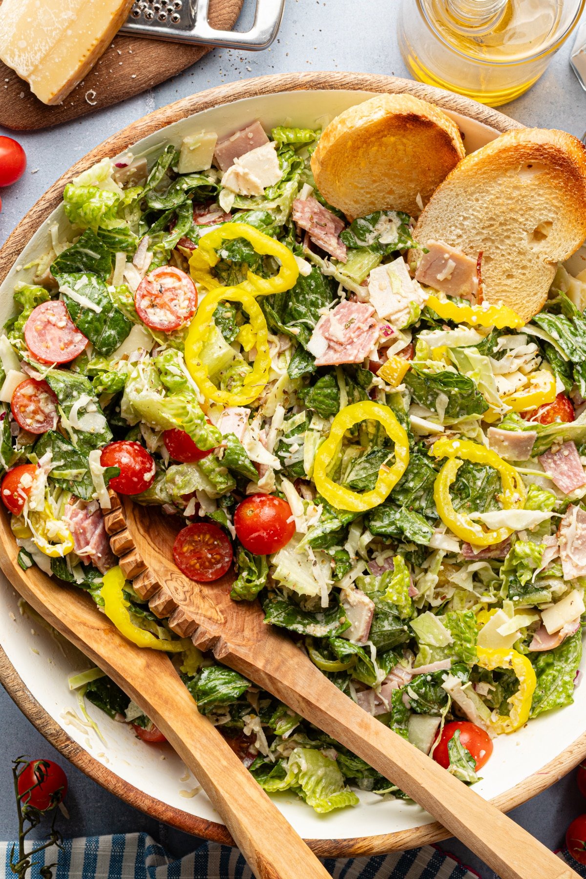 Italian grinder salad in a bowl with crostini and tongs.