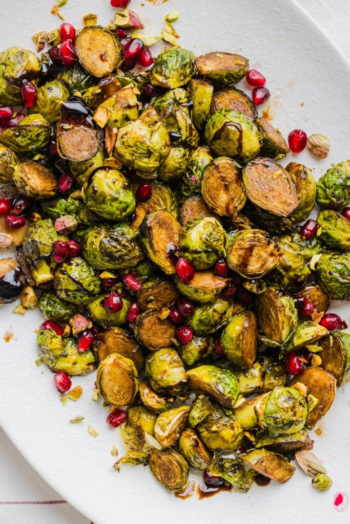 Roasted maple balsamic brussels sprouts topped with pomegranate seeds and pistachios.