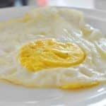 One over hard egg on a white plate.