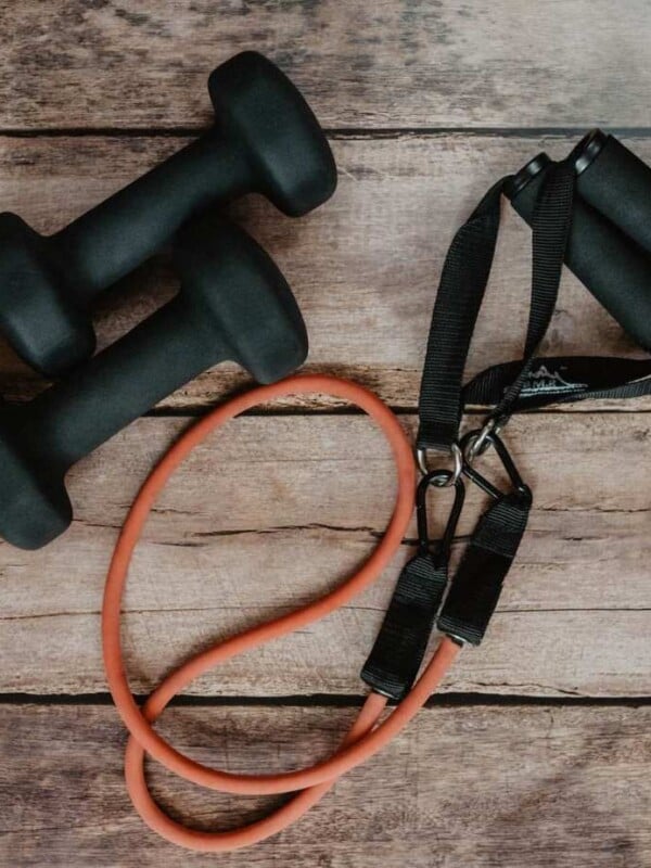 Dumbells and a resistance band on a wooden floor.