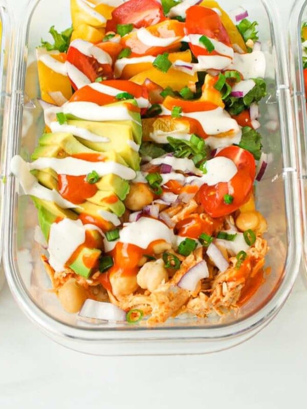 Three containers of buffalo chicken rice bowls lined up on a countertop.