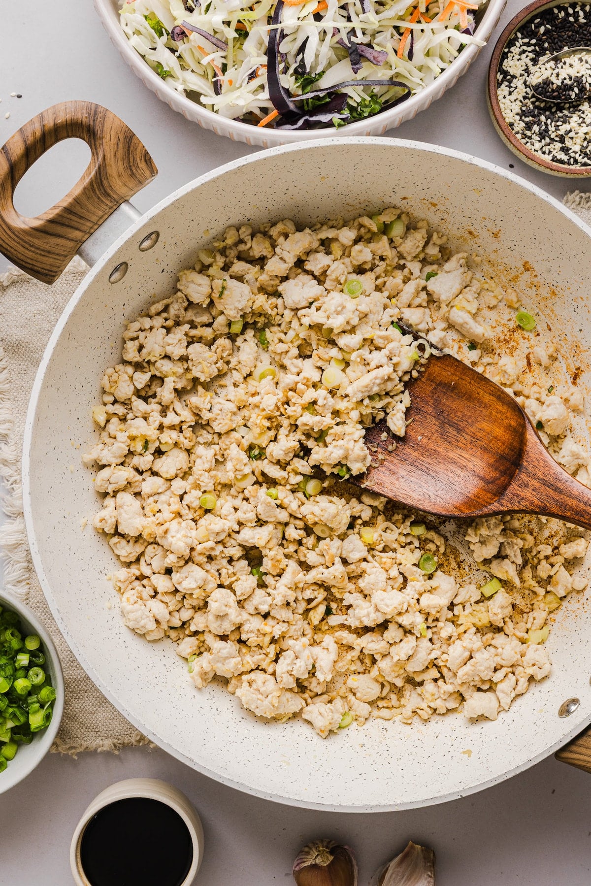 Ground meat and onion with garlic and ginger being sautéed in a pan.