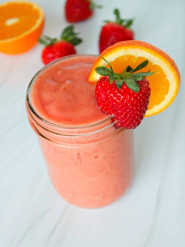 Sunrise sunset tropical smoothie garnished with a strawberry and orange slice.