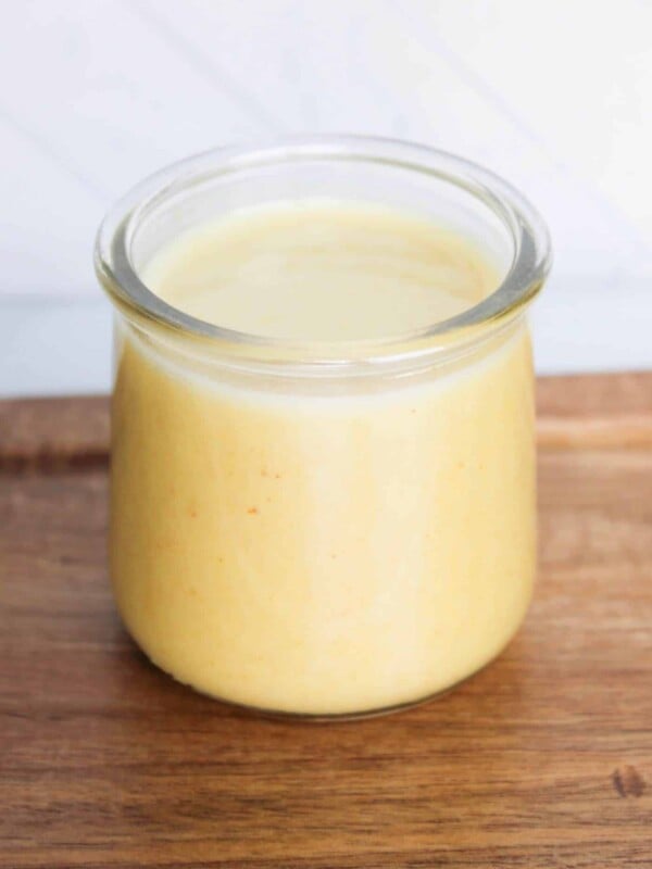 A small bottle of sweet onion dijon vinaigrette on a wooden board.