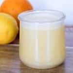 Citrus balsamic vinaigrette in a glass jar on a wooden board with an orange and lemon.