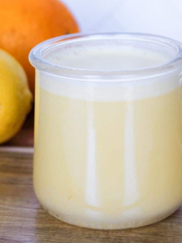 Citrus balsamic vinaigrette in a glass jar on a wooden board with an orange and lemon.