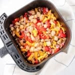 Air fryer stir fry chicken and vegetables in an air fryer basket.