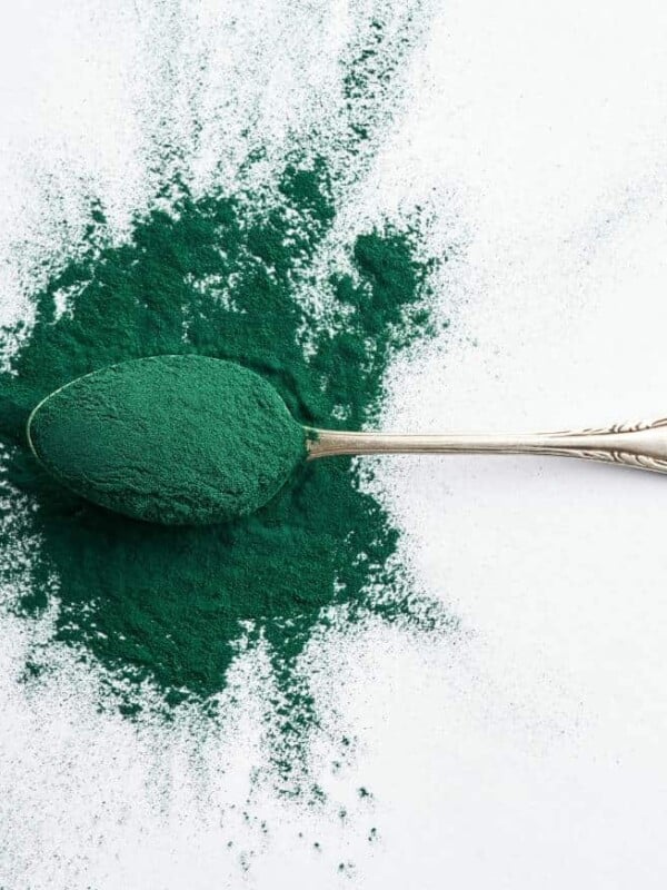 A metal spoon full of overflowing greens powder on a countertop.