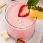 A Tropical Smoothie Bahama mama smoothie in a glass with strawberry and pineapple.