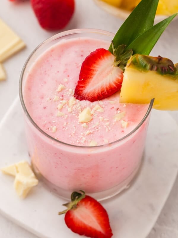 A Tropical Smoothie Bahama mama smoothie in a glass with strawberry and pineapple.