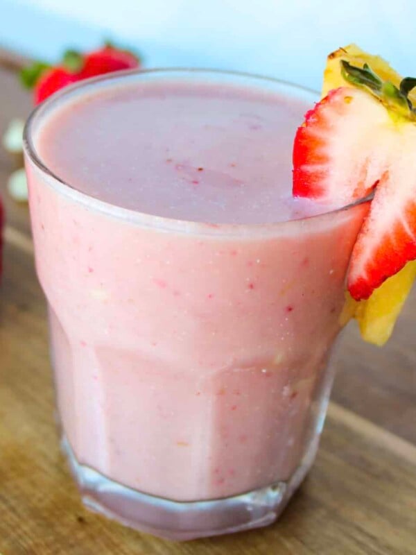 Bahama mama smoothie in a clear glass garnished with a strawberry and pineapple slice.