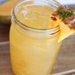 A mason jar of mango pineapple refresher Dunkin donuts copycat drink garnished with a pineapple.