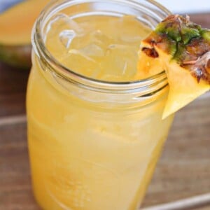 A mason jar of mango pineapple refresher Dunkin donuts copycat drink garnished with a pineapple.
