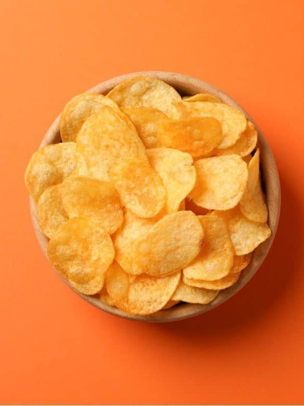 A bowl of chips on an orange background.