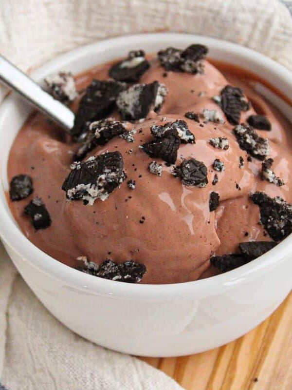 A bowl of chocolate cottage cheese ice cream made with the ninja creami machine in a small white bowl, topped with crushed Oreos.