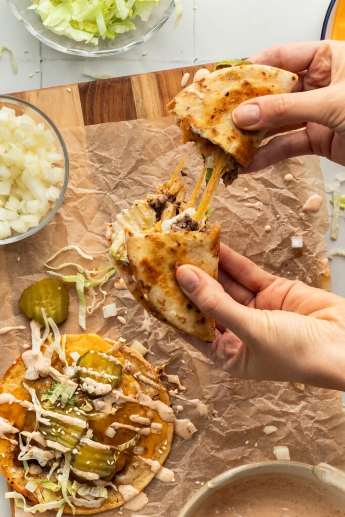 A smash burger taco being pulled apart with a cheese pull.