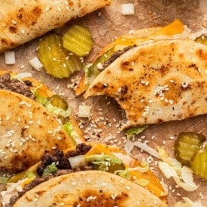 Big Mac tacos on a parchment paper garnished with sesame seeds and pickles