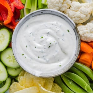 Ranch dip with cottage cheese in a bowl on a vegetable plate with various cut vegetables.