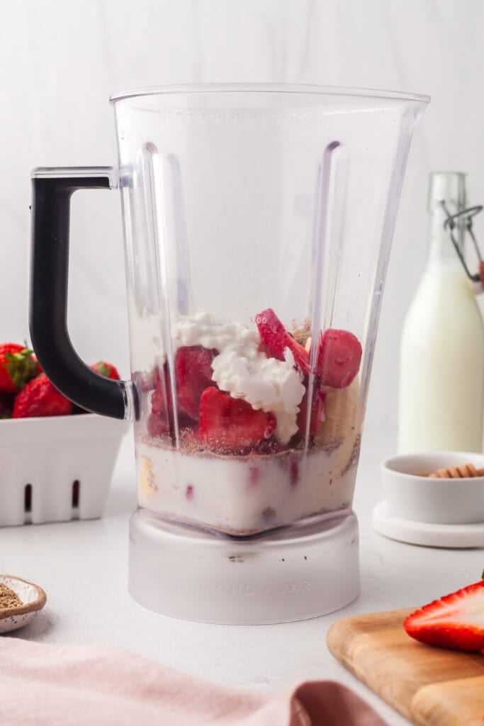 Strawberries, banana, cottage cheese, milk, flaxseed and honey in a blender.