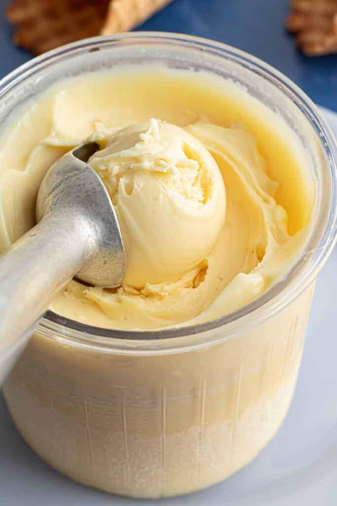A Ninja Creami pint container full of protein ice cream with an ice cream scoop.