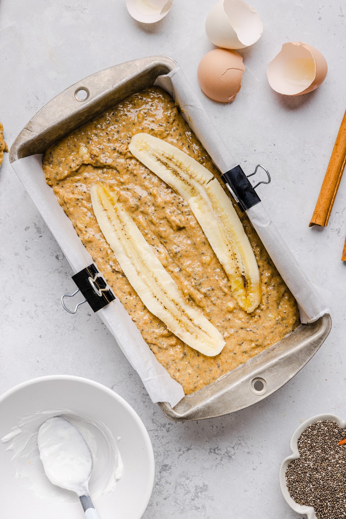 Banana bread batter in a loaf pan topped with sliced banana.