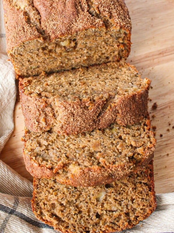 A shot of a loaf of chia seed banana bread with thick slices on a wooden board.