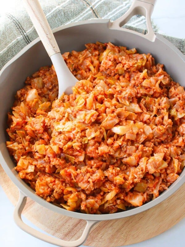 A skillet full of unstuffed cabbage roll with a large serving spoon.