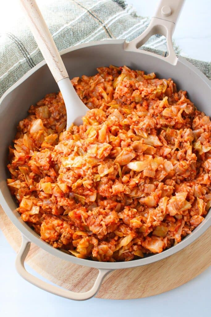 A skillet full of unstuffed cabbage roll with a large serving spoon.