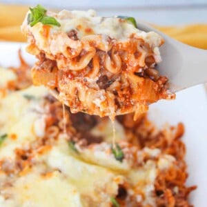 A close up shot of a scoop of deconstructed lasagna on a serving spoon.