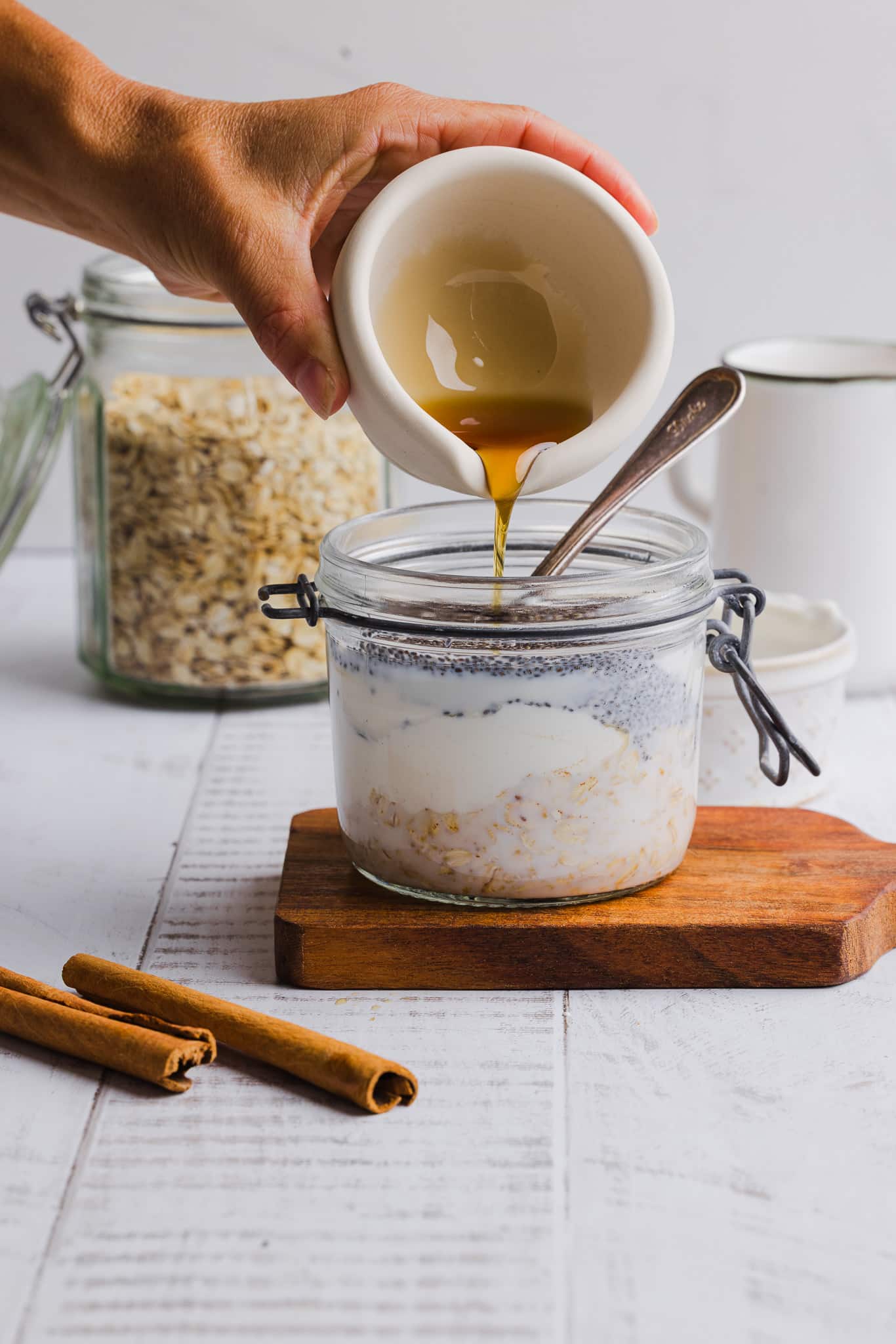 Ingredients for maple brown sugar overnight oats being added to a jar.