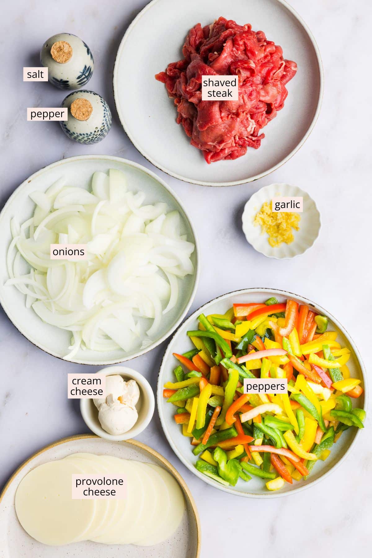 Philly cheesesteak casserole inredients on a countertop with labels.