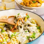 Philly cheesesteak casserole being scooped out with a wooden spoon.